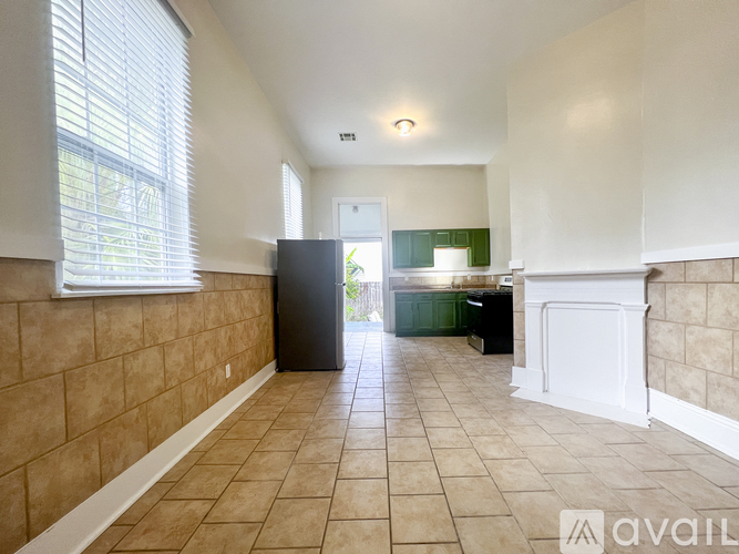 A kitchen area with a black refrigerator and white cabinets.