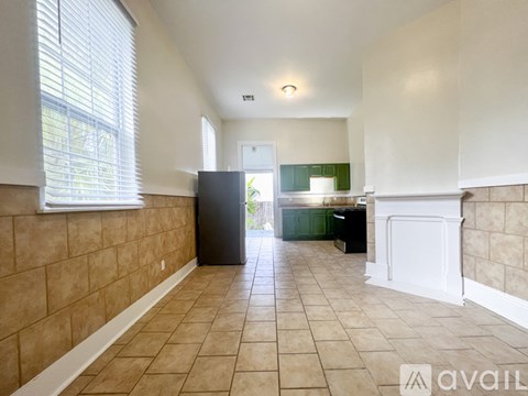 A kitchen area with a black refrigerator and white cabinets.