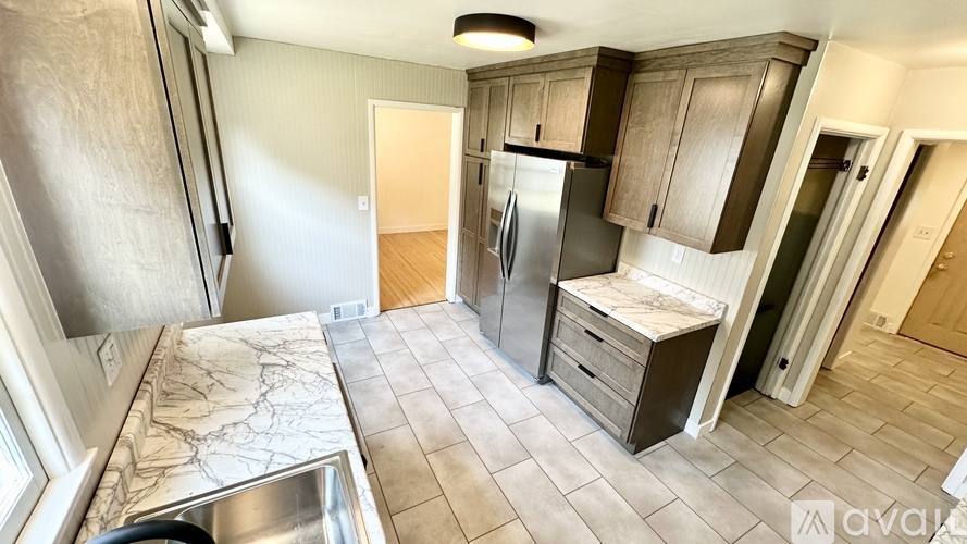 A kitchen with a sink, refrigerator, and cabinets.