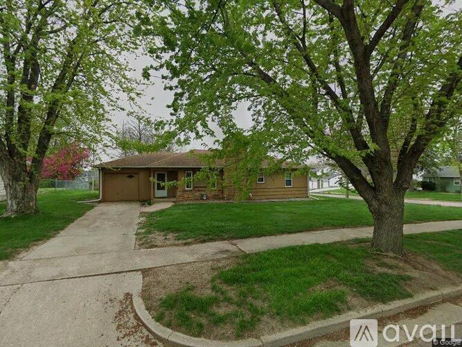 A house with a brown roof and a brown door is surrounded by trees.