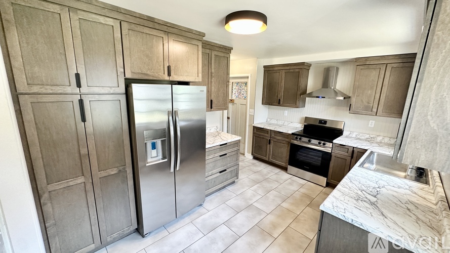 A kitchen with a refrigerator, oven, and sink.