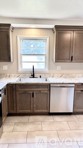 A kitchen with brown cabinets and a white dishwasher.