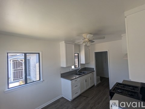 A kitchen with white cabinets and a window with blinds.