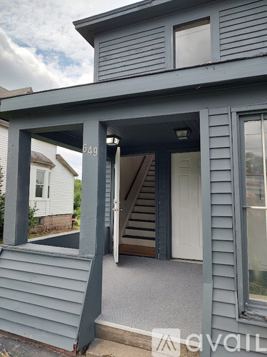 A house numbered 849 with a grey siding and a white door.