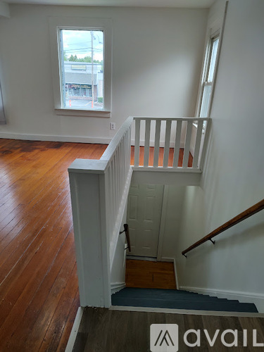 A wooden staircase with a white railing and a window overlooking a street.