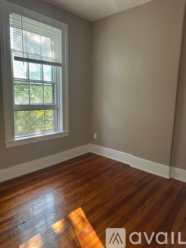 A room with wooden floors and a window with blinds.
