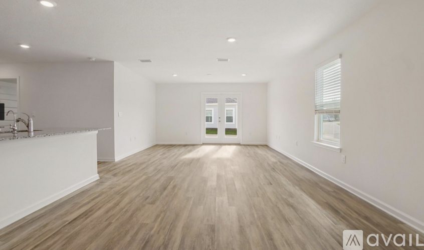 A spacious room with wooden flooring and white walls.