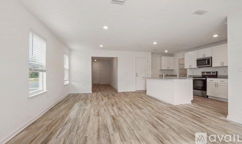 A spacious kitchen with white cabinets and a wooden floor.
