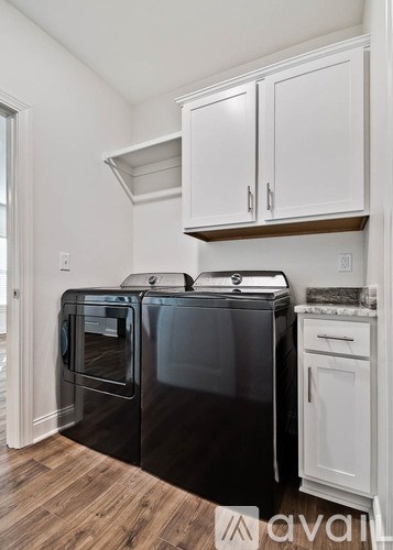A black dishwasher is in a kitchen with white cabinets.