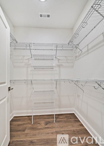 A white walk in closet with shelves and a wooden floor.