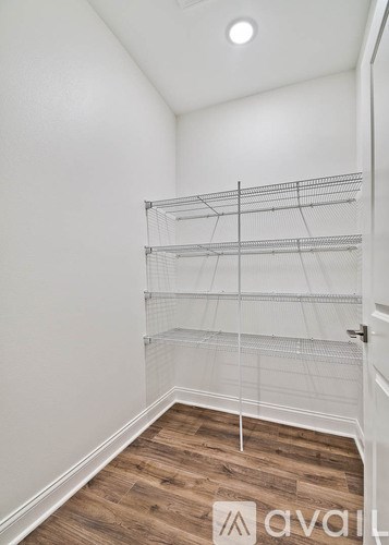 A room with a white wall and a wooden floor with a shelving unit.