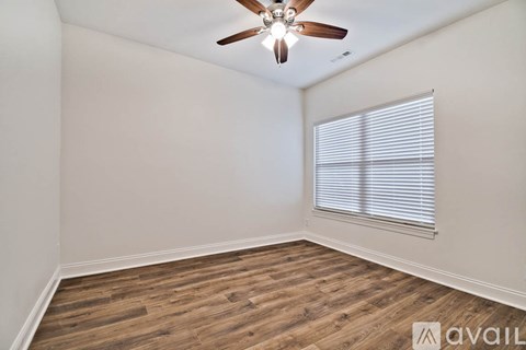A room with a ceiling fan and wooden flooring.
