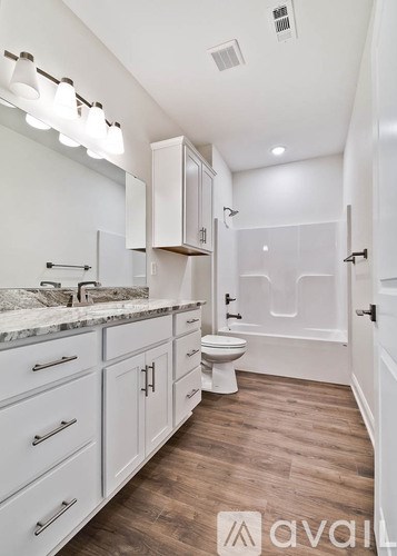 A bathroom with a toilet, sink, and cabinets.