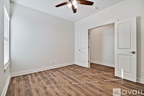 A room with a ceiling fan and wooden flooring.