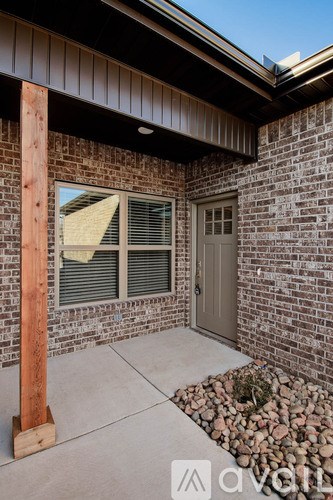 A house with a brown wooden post in front of a brick wall.