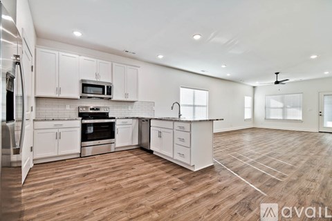 A spacious kitchen with white cabinets and wooden flooring.