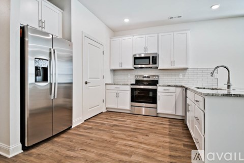 A kitchen with a stainless steel refrigerator and wooden flooring.