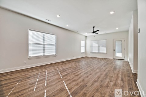 A spacious room with wooden flooring and a ceiling fan.