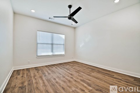 A room with a ceiling fan and wooden flooring.