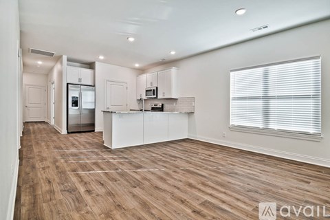 A spacious kitchen with white cabinets and a refrigerator.