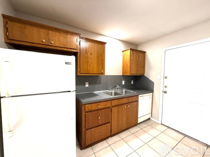 A kitchen with a white refrigerator, wooden cabinets, and a black countertop.