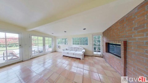 A living room with a white couch and a brick wall.