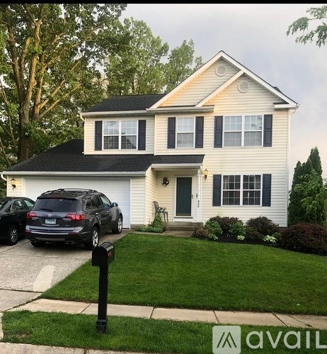 A two-story house with a garage and a car parked in front.
