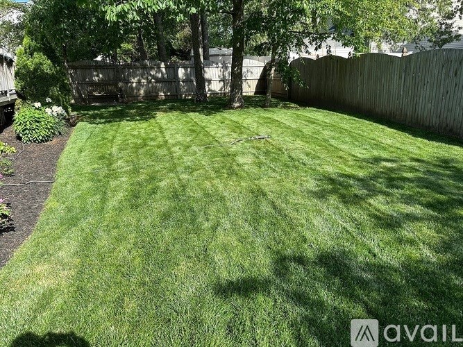 A backyard with a well-maintained lawn and a wooden fence.
