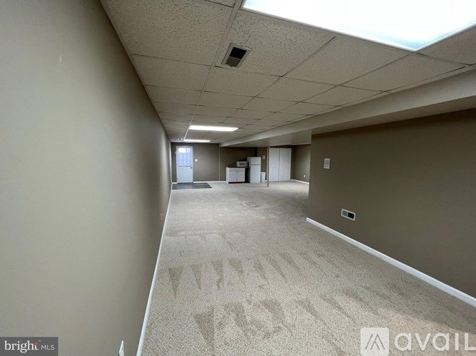 A long hallway with carpeted floors and fluorescent lighting.
