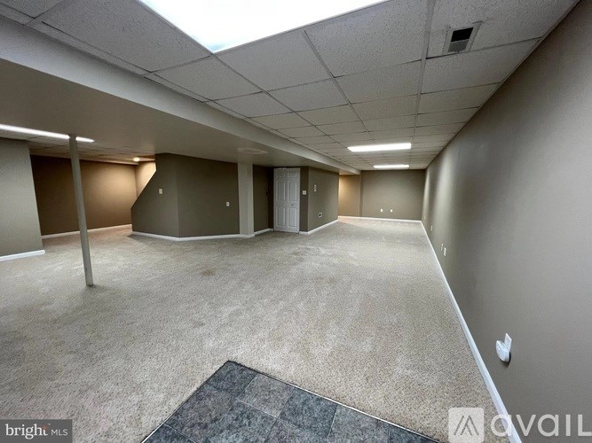 A spacious office room with a carpeted floor and a skylight.