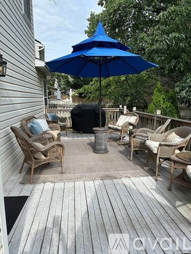 A blue umbrella is on a patio with chairs and a table.