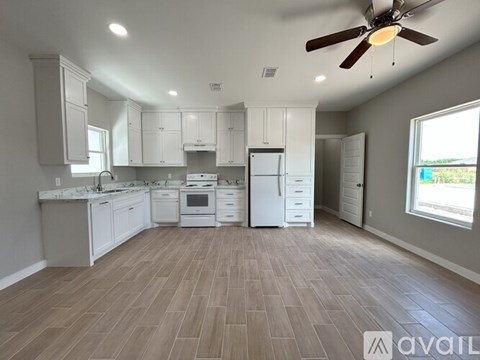 A spacious kitchen with white cabinets and a fan on the ceiling.