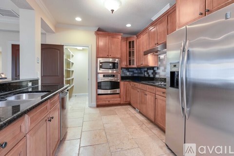 A kitchen with wooden cabinets and a stainless steel refrigerator.
