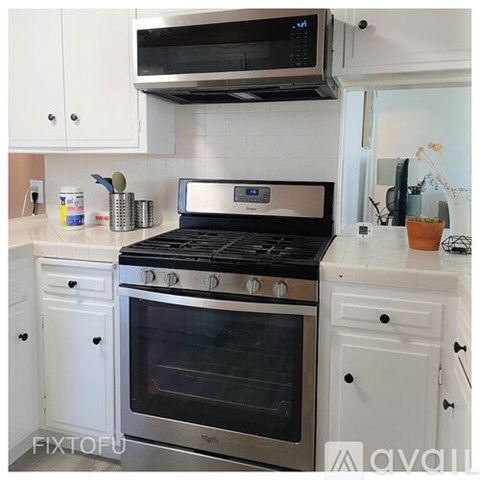 A modern kitchen with a stove top oven and a microwave above it.