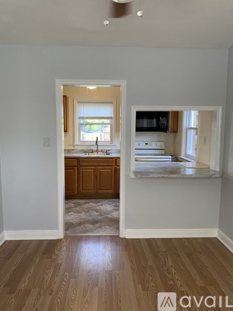 A kitchen with a window and a sink is visible from the living room.