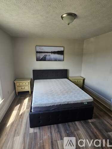 A bedroom with a bed, nightstand, and a picture on the wall.