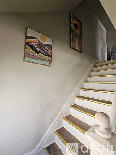 A staircase with a white banister and a painting on the wall.
