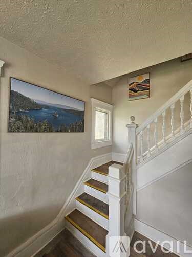 A staircase with a painting of a beach scene on the wall.