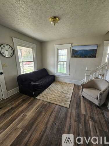 A living room with a black couch and a wooden floor.