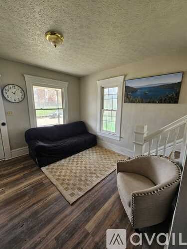 A living room with a couch, chair, and a clock on the wall.