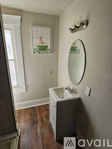 A bathroom with a round mirror and a cabinet.