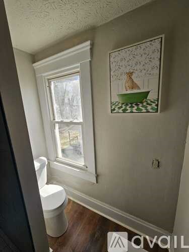 A bathroom with a toilet and a painting of a vase on the wall.