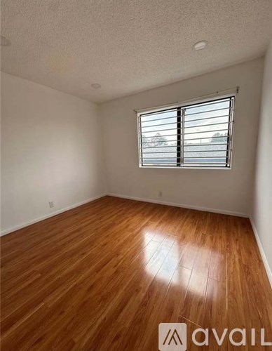 A room with wooden flooring and a window with blinds.