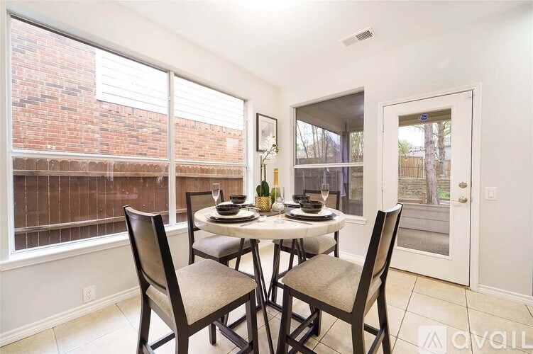 A dining room with a table set for two and chairs around it.