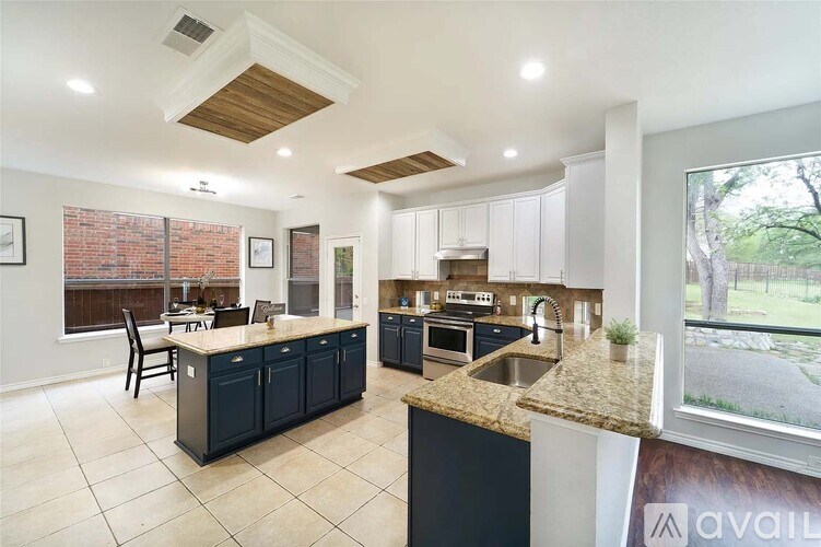 A kitchen with a black countertop and a window overlooking a tree-lined street.