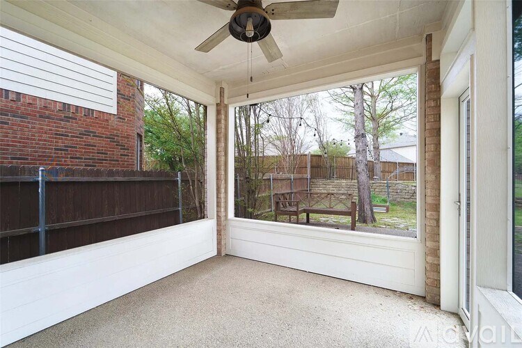 A patio with a ceiling fan and a view of a backyard.