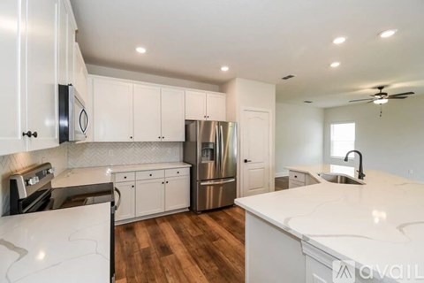 A modern kitchen with white cabinets and stainless steel appliances.