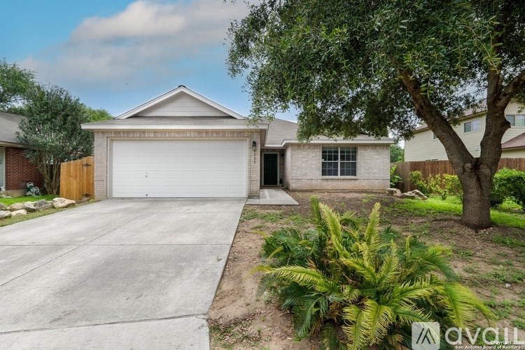 A house with a garage and a tree in front.