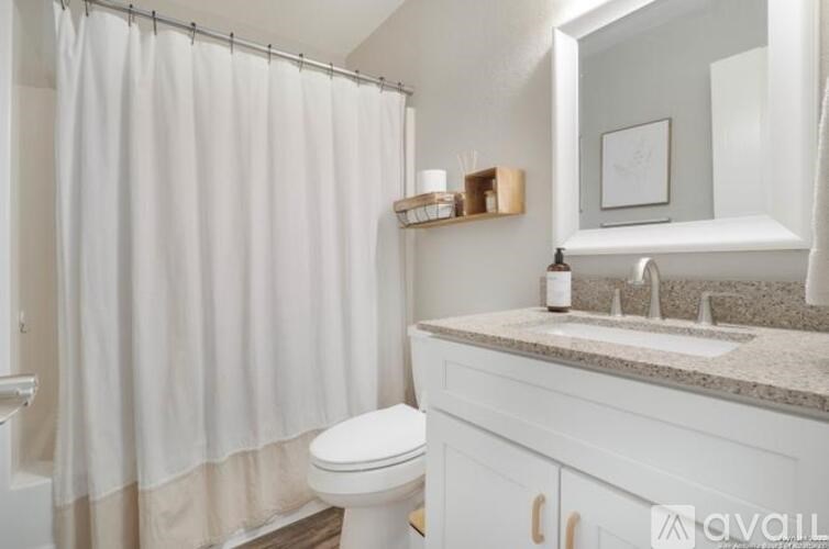 A white bathroom with a toilet, sink, and shower curtain.