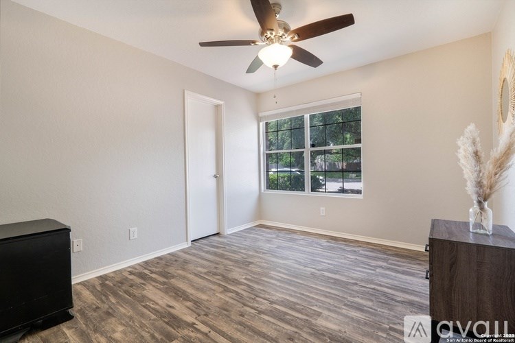 A room with a ceiling fan and a window with a view of trees.